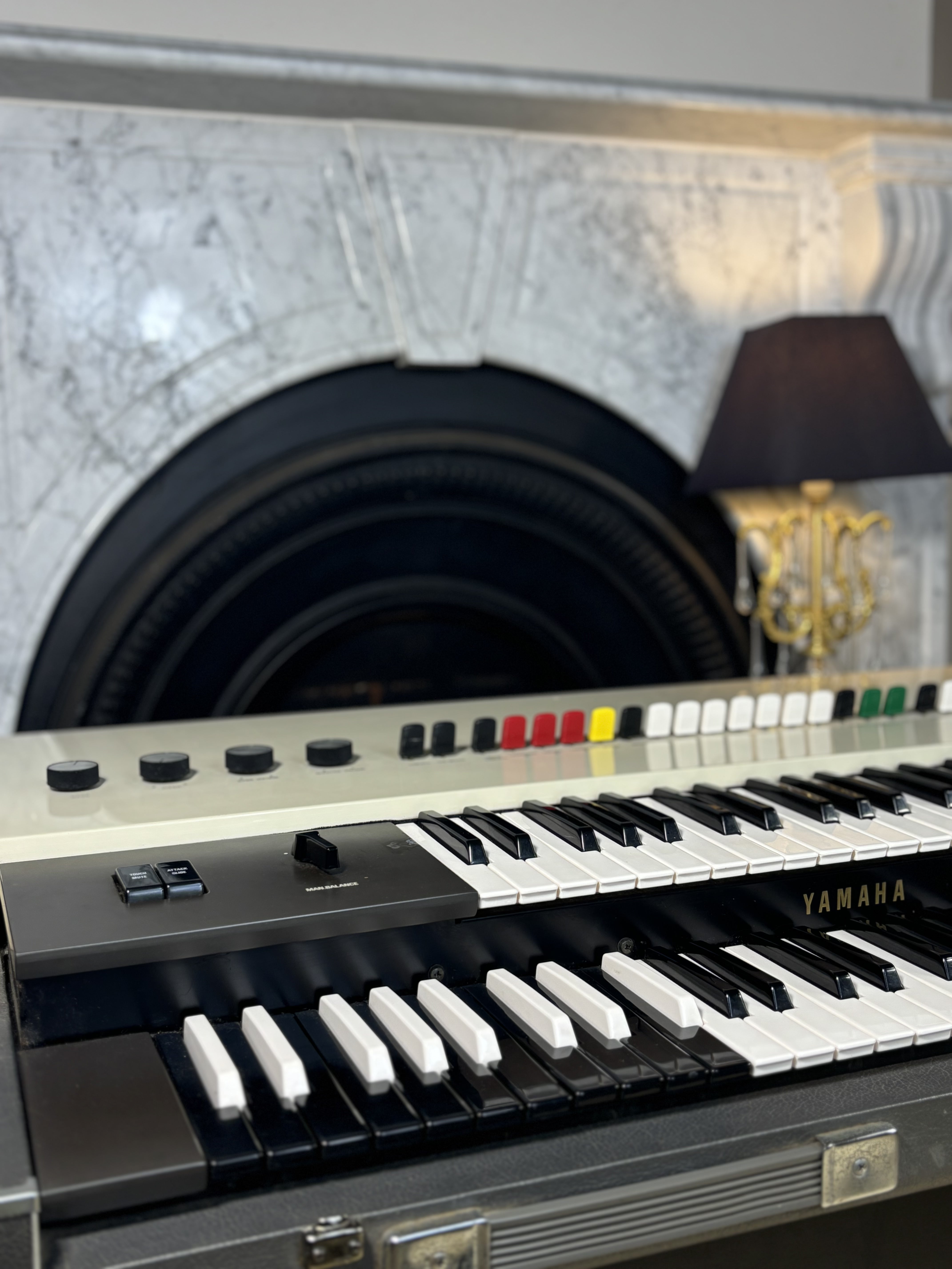 Yamaha keyboard in a decorative setting with a lamp and marble wall.