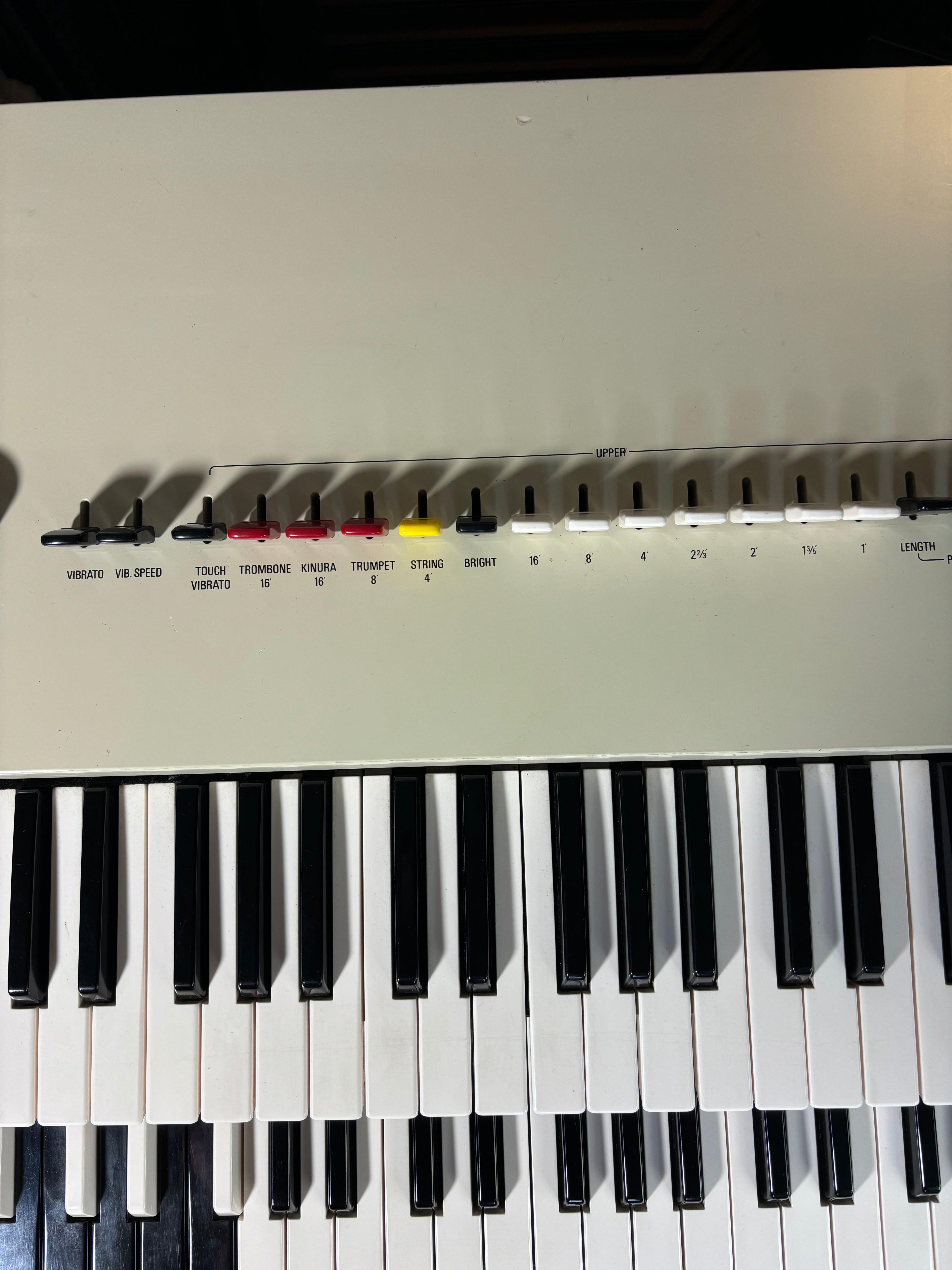 Close-up of a keyboard with control knobs and labels on a white background